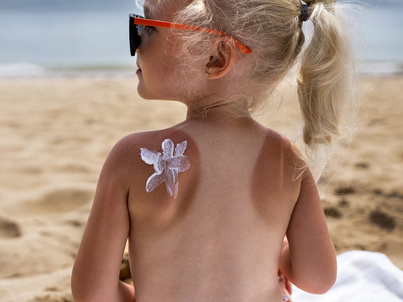 Un bébé avec une fleur en crème solaire sur le haut du dos