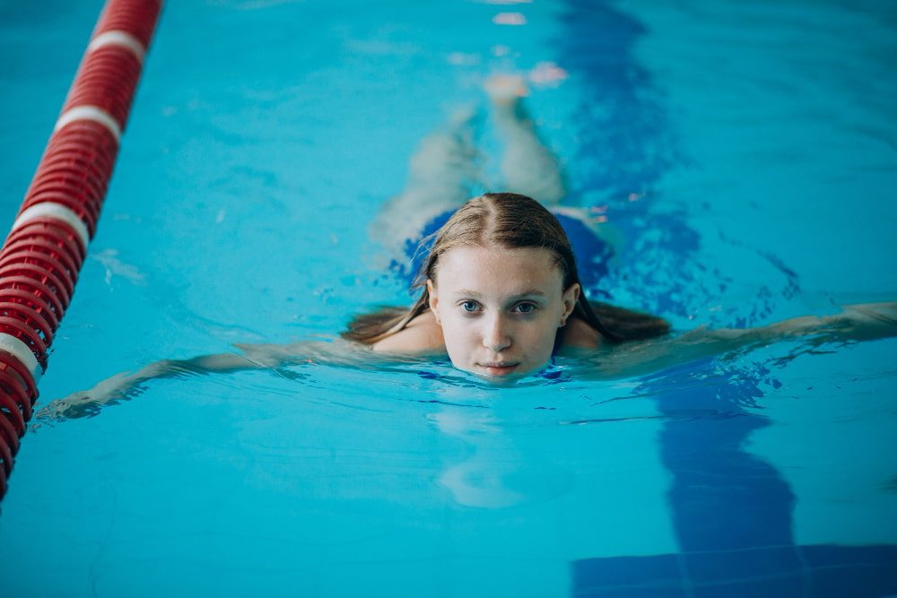 Comment apprendre la nage papillon : une enfant nage le papillon dans une piscine