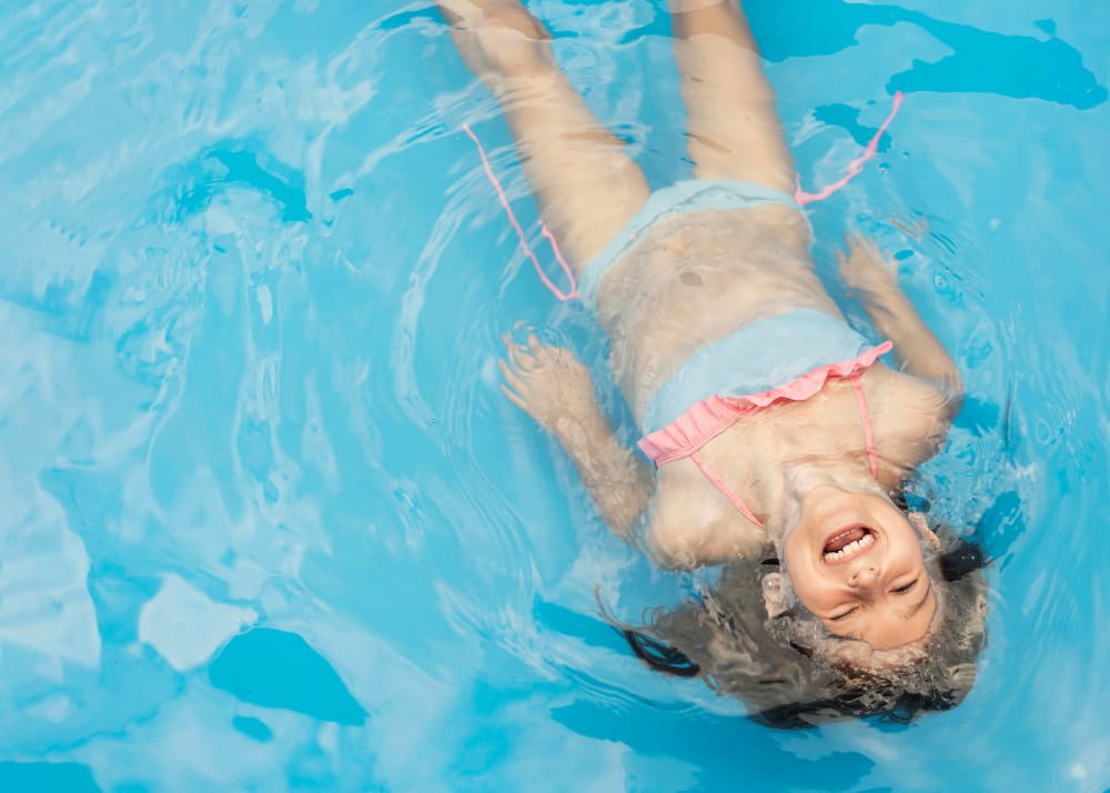 Une petite fille apprend à s'allonger dans l'eau