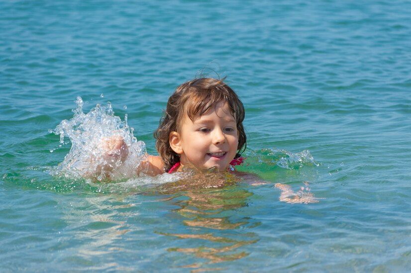 Comment apprendre à nager sur le ventre : une enfant nage sur le ventre dans la mer