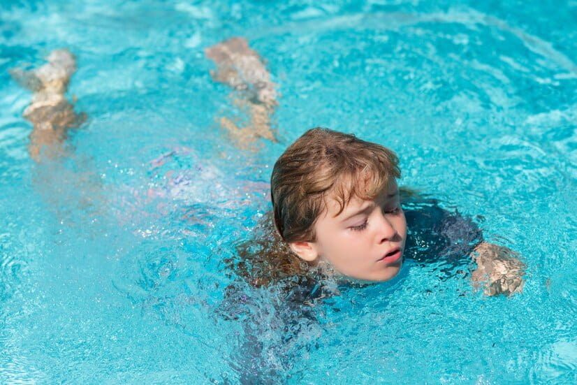 Un enfant nage dans une piscine après avoir fait un plongeon canard