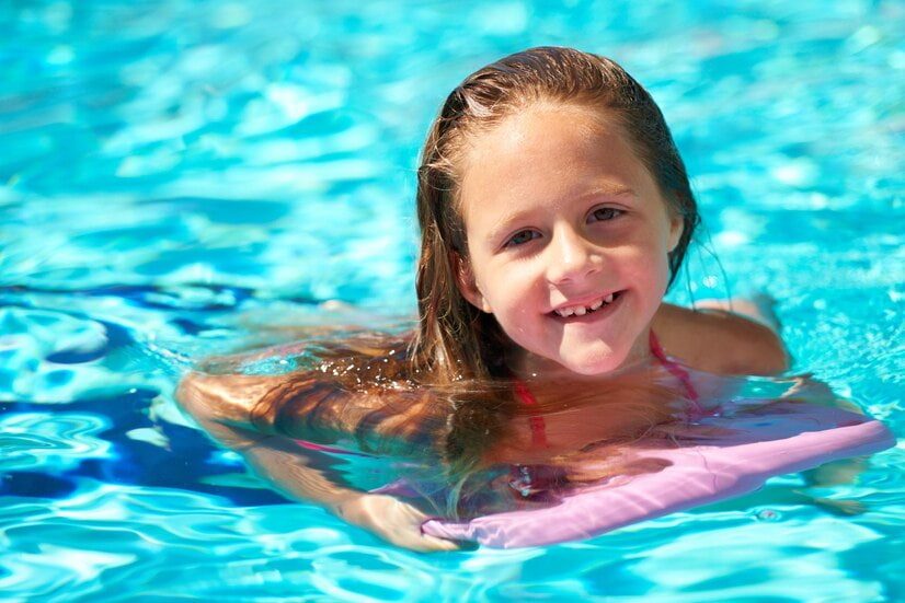 Une enfant apprend à s'allonger dans l'eau avec une planche